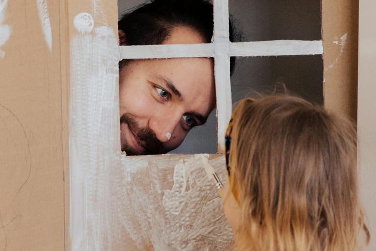 a man and a little girl playing with cardboard boxes