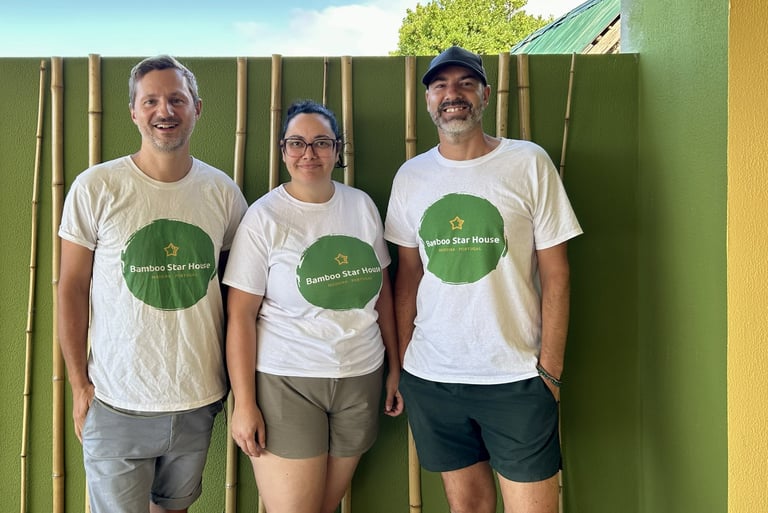 Three people wearing Bamboo Star House Madeira shirts standing in front of a green bamboo wall.