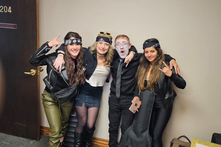 Four people posing in biker costumes with bandanas, leather jackets, and face paint at a costume party.