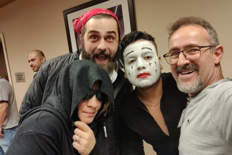 A diverse group of friends in creative costumes, including white face paint makeup and a hooded cloak.