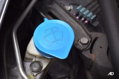 A blue windshield wiper fluid reservoir cap located inside a car engine bay for vehicle maintenance.