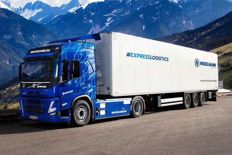 a blue truck with a trailer in the mountains