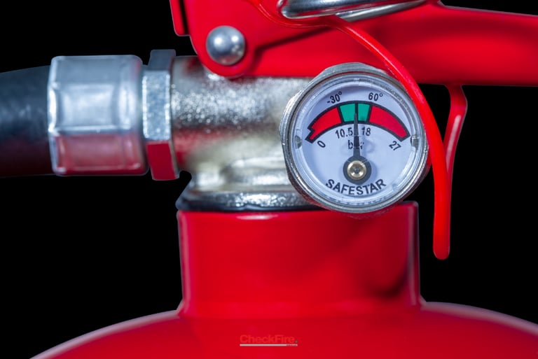 Close-up of a red fire extinguisher pressure gauge showing needle in the green zone for safety.