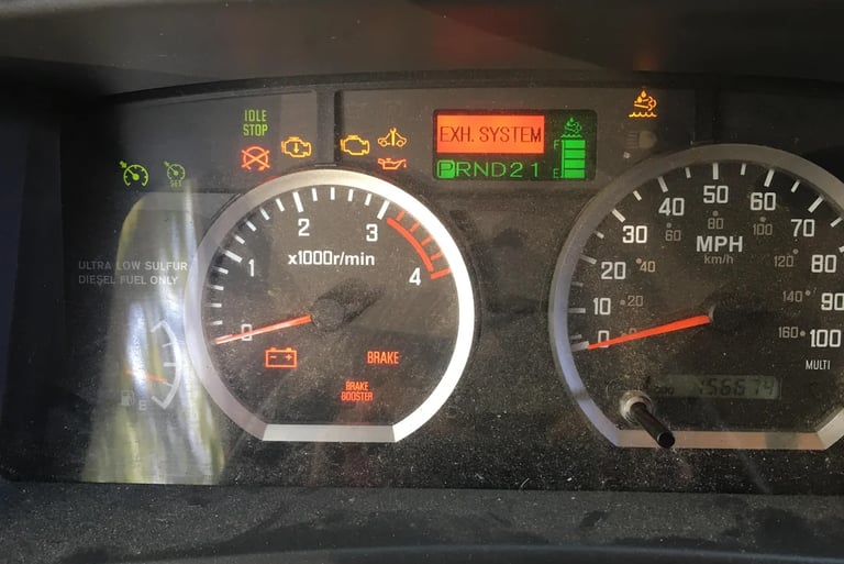 Truck dashboard displaying active warning lights including exhaust system, battery, and brake alerts.