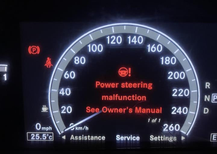 Digital car dashboard displaying a red power steering malfunction warning message and service alert.