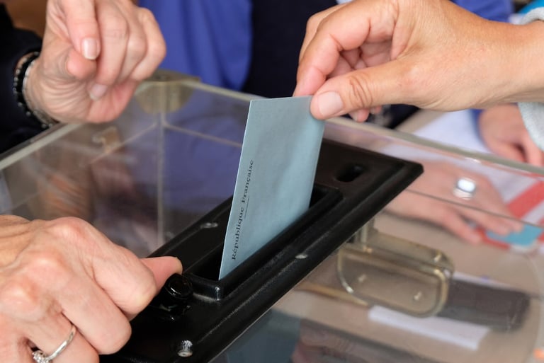 Photo d'une enveloppe glissée dans une urne évoquant le vote et l'élection