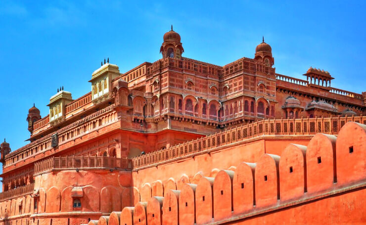 Red sandstone architecture of Junagarh Fort in Bikaner under a clear blue sky.