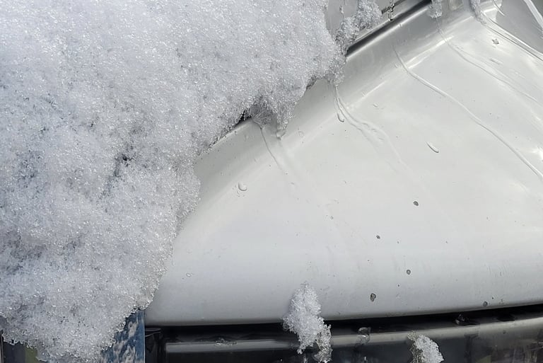 close up picture of snow melting off the hood of a truck
