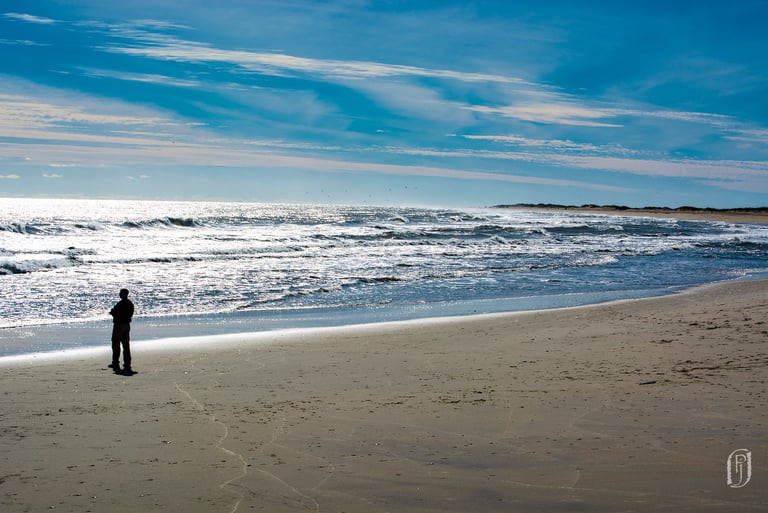 Photo of solitary man on beach looking out to sea