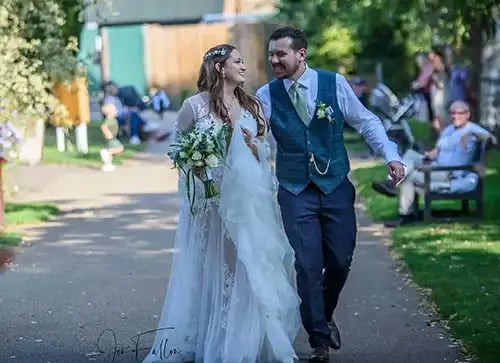 Smiling bride and groom walking together outdoors in Abbey Gardens Bury St Edmunds