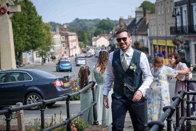 A smiling groom in a plaid waistcoat walking towards Bury St Edmunds Registry Office