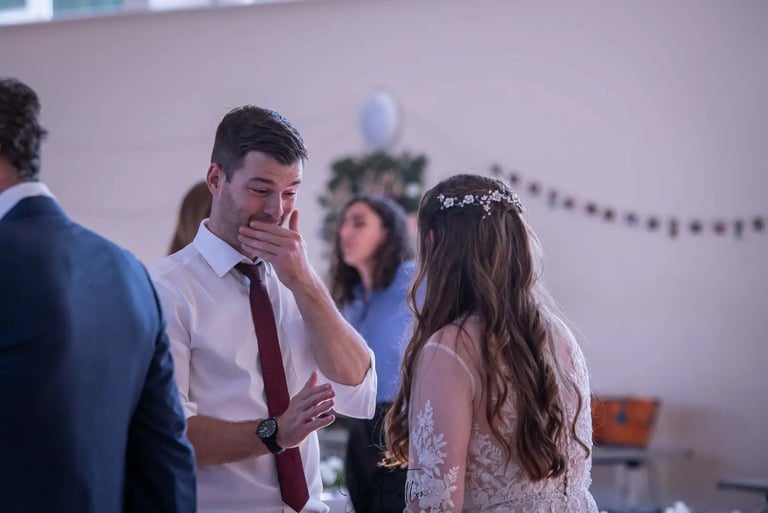 An emotional wedding guest crying while talking to a bride in a white lace dress.