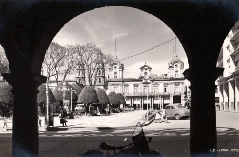 Vintage view of Leon, Guanajuato, Mexico, featuring historic architecture and park through an archway.