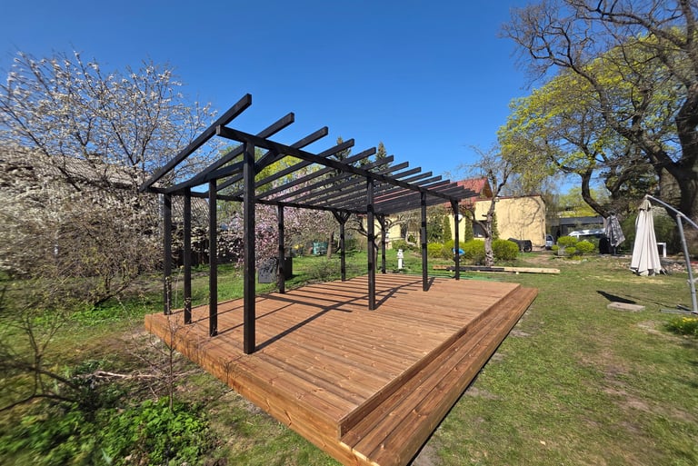 Medinė terasa, kurios dalį dengia pergola.