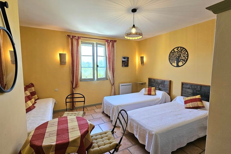 chambre Ocre de "la ramade" avec 2 lits séparés, une table et miroir rond, mur ton jaune ocre.