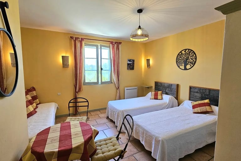 chambre Ocre de "la ramade" avec 2 lits séparés, une table et miroir rond, mur ton jaune ocre.