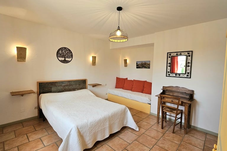 Chambre Olivier avec un grand lit, un bureau et un canapé dans une ambiance provençale. 
