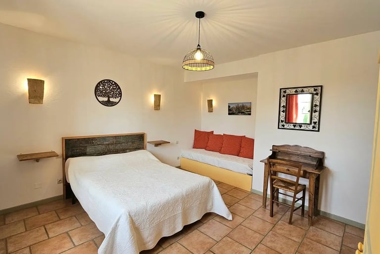 Chambre Olivier avec un grand lit, un bureau et un canapé dans une ambiance provençale. 