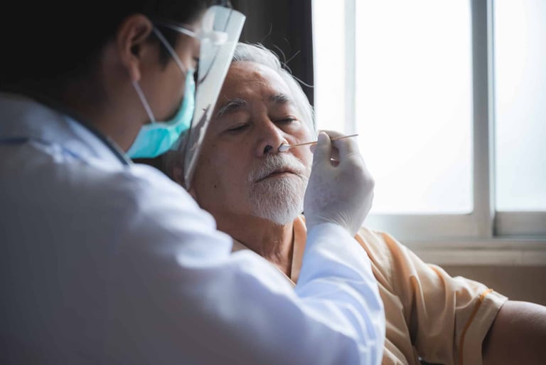 A healthcare professional in PPE performing a nasal swab test on an elderly man.