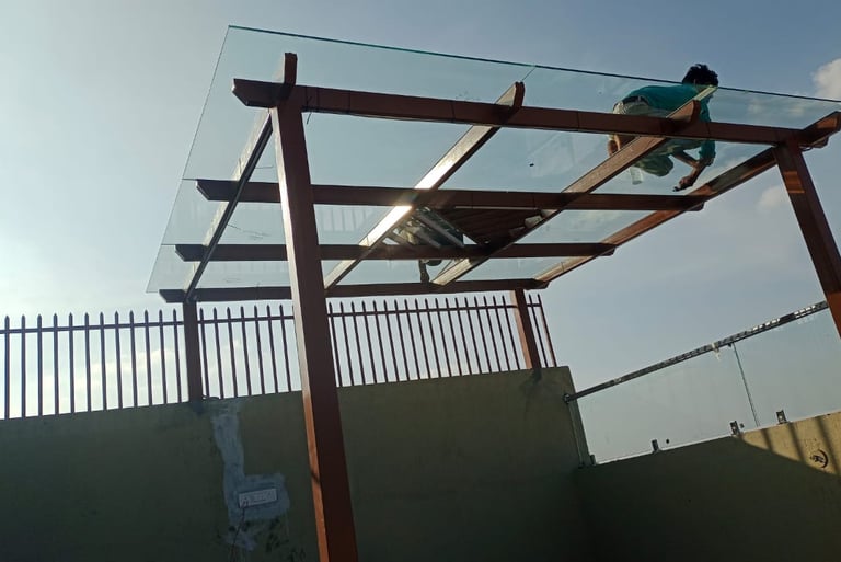 Minimalist glass pergola with a dark metal frame installed on a modern residential terrace.
