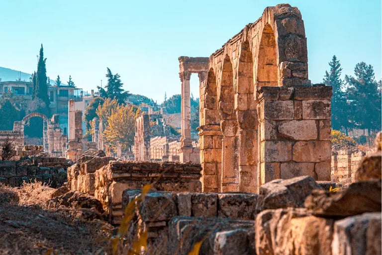 Ancient stone arches and columns at the archaeological ruins of Anjar, Lebanon under a clear blue sky.