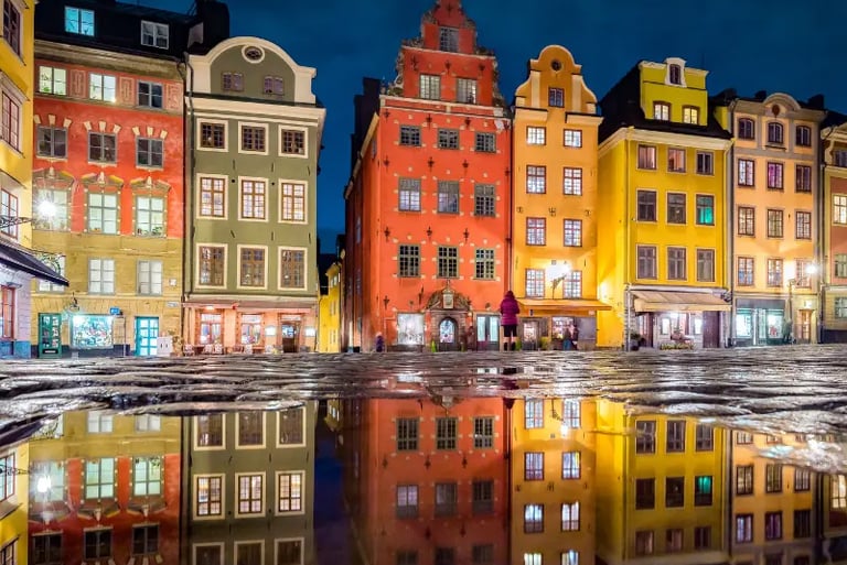 Colorful historic buildings in Stortorget square, Gamla Stan, Stockholm reflected in a rain puddle at night.