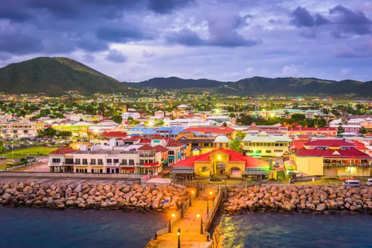 Aerial view of Basseterre, St. Kitts at dusk featuring colorful waterfront buildings and harbor.