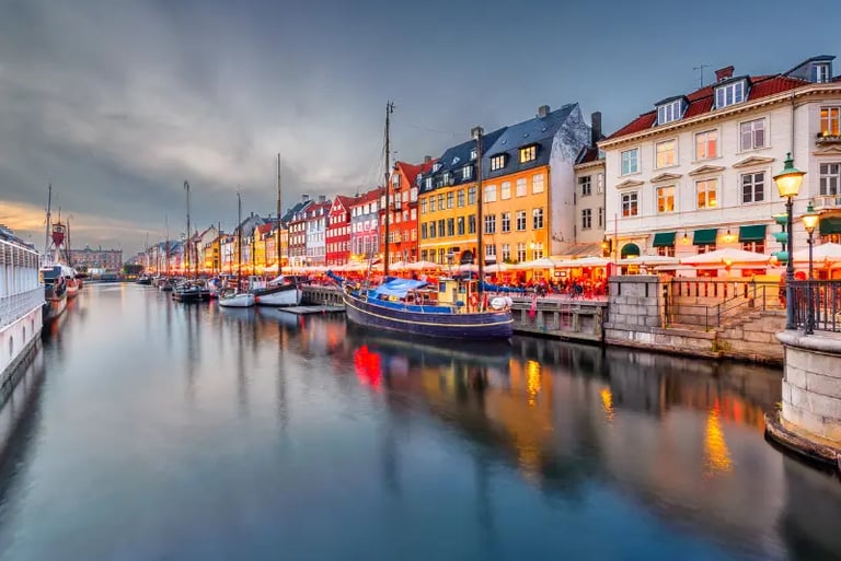 Colorful historic buildings and wooden boats in Nyhavn canal, Copenhagen, at twilight.