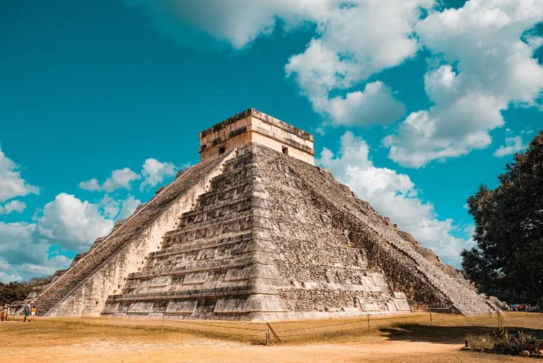 The El Castillo pyramid at Chichen Itza, a famous Mayan archaeological site in Mexico under a blue sky.