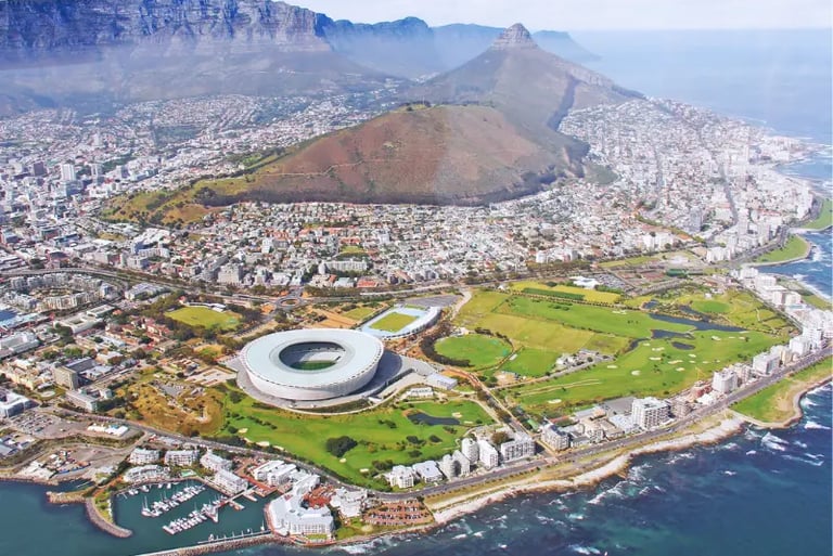 Aerial view of Cape Town Stadium and Table Mountain overlooking the coastal city landscape.