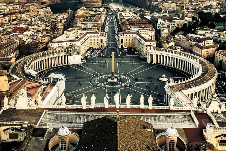 Aerial view of St. Peter's Square and the Vatican City cityscape featuring the iconic Egyptian obelisk.