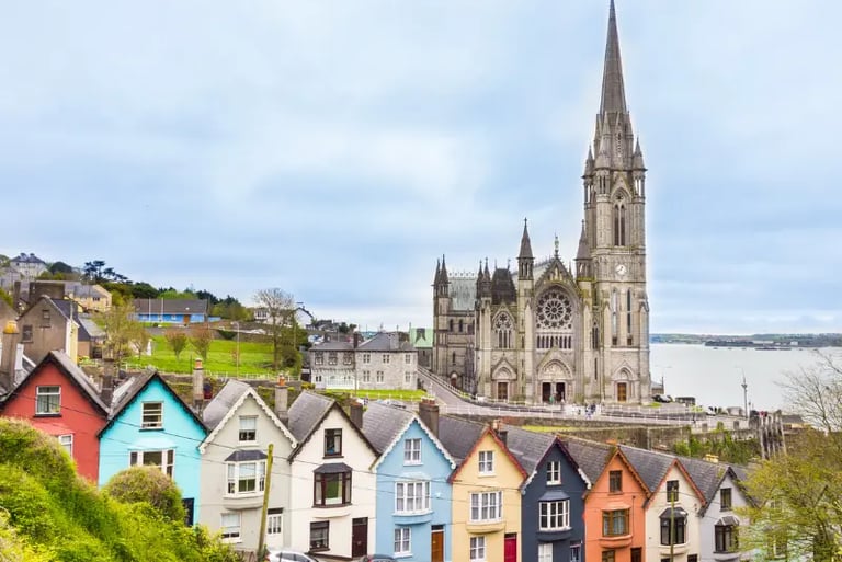 The colorful Deck of Cards houses in Cobh, Ireland, with St. Colman's Cathedral and the harbor in the background.