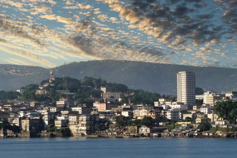 Panoramic view of the Freetown Sierra Leone skyline along the coast under a dramatic sunset sky.