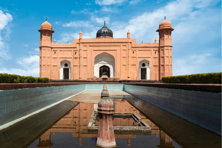 Mausoleum of Bibi Pari at Lalbagh Fort in Dhaka with a reflective pool under a blue sky.