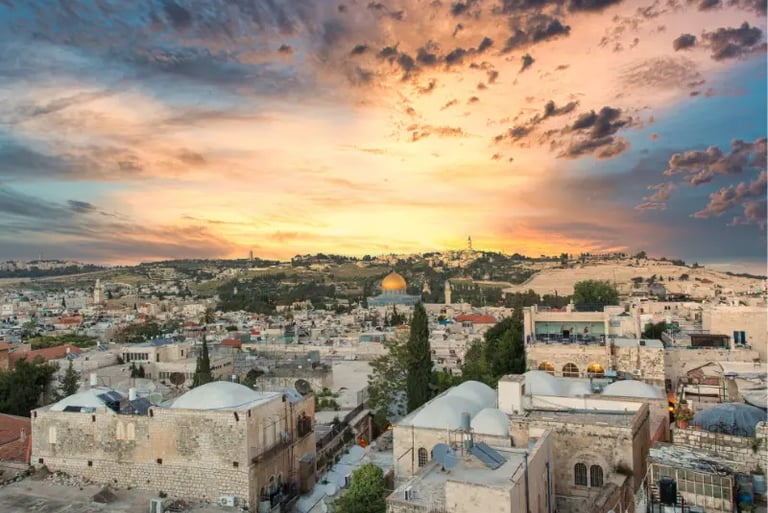 Jerusalem Old City skyline with Dome of the Rock under a vibrant sunset sky.