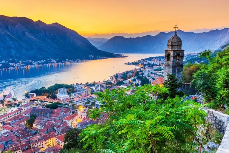 Sunset view over the Bay of Kotor in Montenegro with historic church tower and mountain scenery.