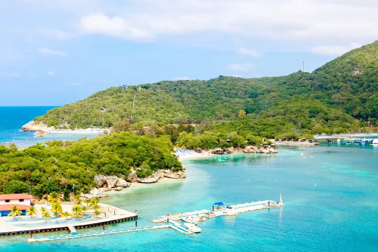 Aerial view of Labadee, Haiti, featuring turquoise Caribbean waters, lush green hills, and a private beach resort dock.