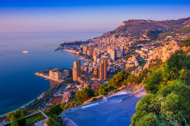 Panoramic sunset view of Monte Carlo, Monaco buildings and coastline from the French Riviera mountains.