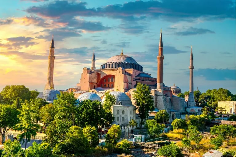 The Hagia Sophia Grand Mosque in Istanbul, Turkey, at sunset with its iconic domes and four minarets.