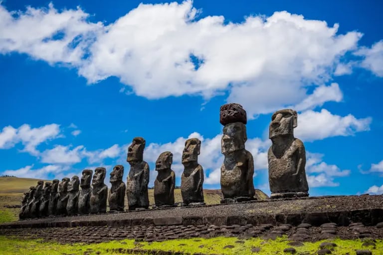 A row of ancient Moai statues standing on Ahu Tongariki under a blue sky on Easter Island.