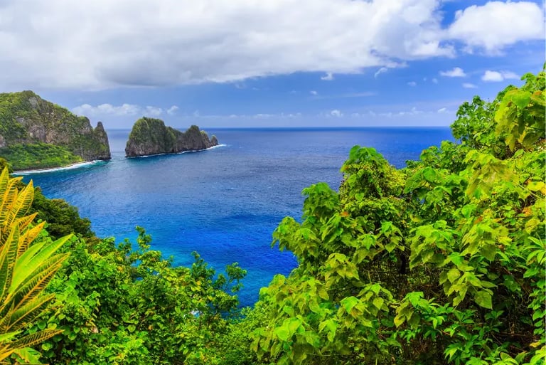 Panoramic view of tropical green cliffs and vibrant blue ocean waters in American Samoa.