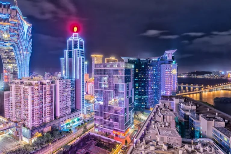 Night view of the Macau skyline featuring illuminated skyscrapers and the Grand Lisboa hotel.