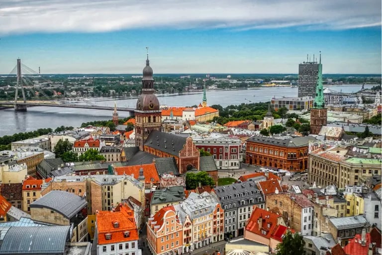Panoramic aerial view of Riga Old Town skyline featuring the Daugava River and historic church spires in Latvia.