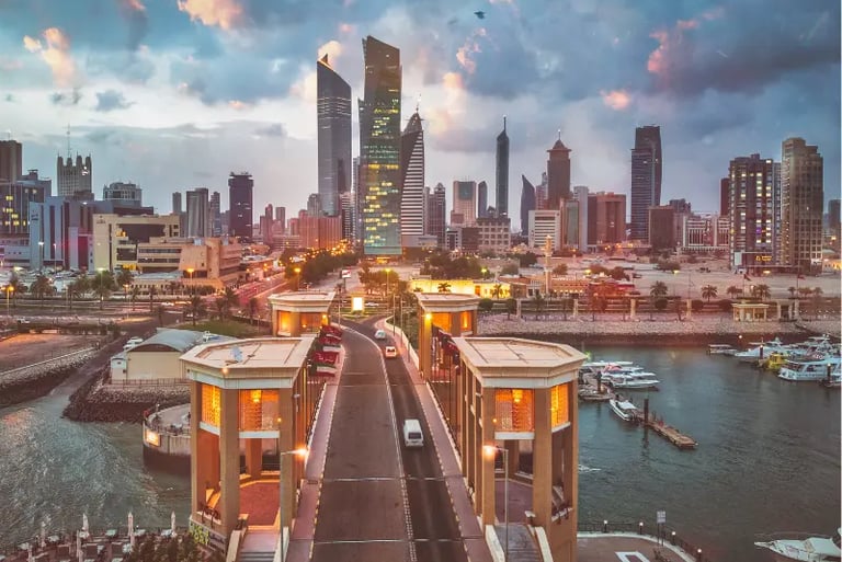 Panoramic sunset view of Kuwait City skyline with modern skyscrapers and the Sharq Marina waterfront.