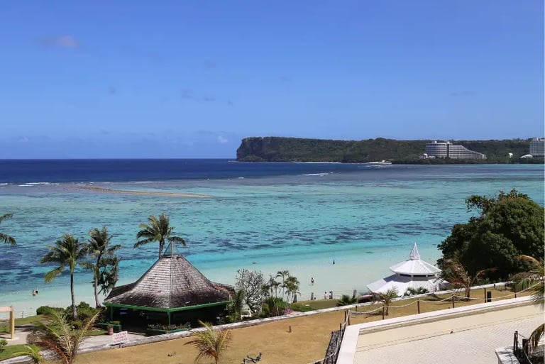 Aerial view of Tumon Bay, Guam beach with turquoise water, palm trees, and Two Lovers Point.