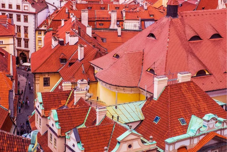 Aerial view of historic Prague architecture featuring traditional orange terracotta tile rooftops and cobblestone streets.
