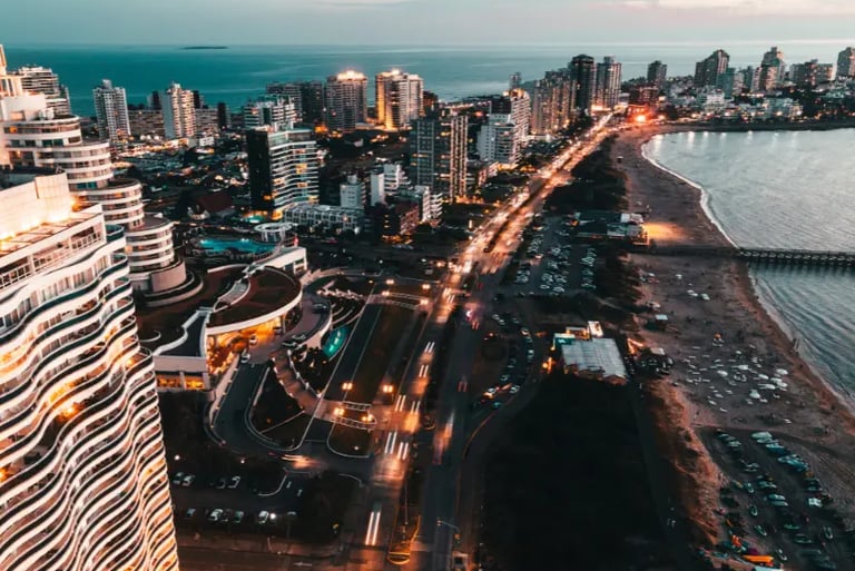 Aerial view of Punta del Este skyline and coastline at sunset with illuminated city lights and beach.