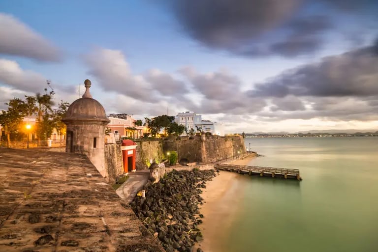 A stone sentry box at Castillo San Felipe del Morro overlooks the Old San Juan coast at dusk.