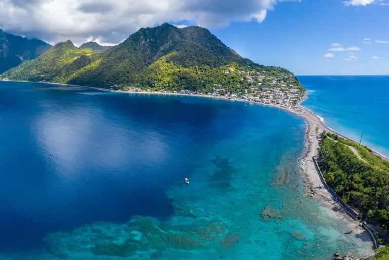Aerial view of Scott's Head in Dominica with clear turquoise Caribbean water and lush green mountains.