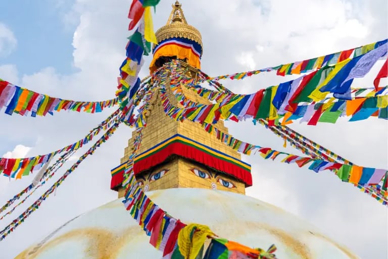 Boudhanath Stupa in Kathmandu Nepal with colorful Tibetan prayer flags under a cloudy sky.